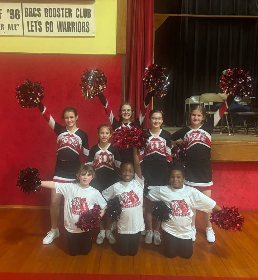 The Blue Ridge Christian School Warriors cheerleading squad poses with pom-poms in the gym