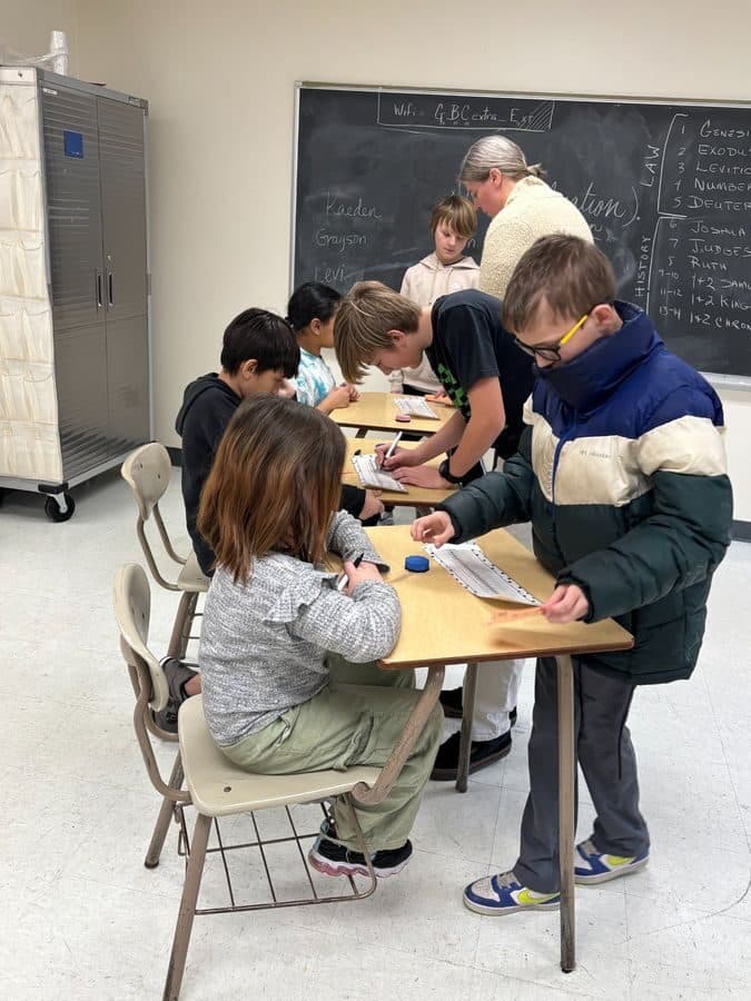 Middle school students working through a Bible history assignment together at their desks