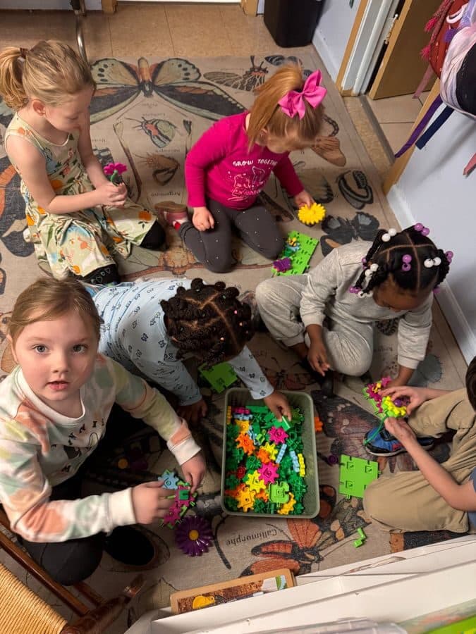 Little Warriors preschoolers playing together with building blocks on the classroom rug